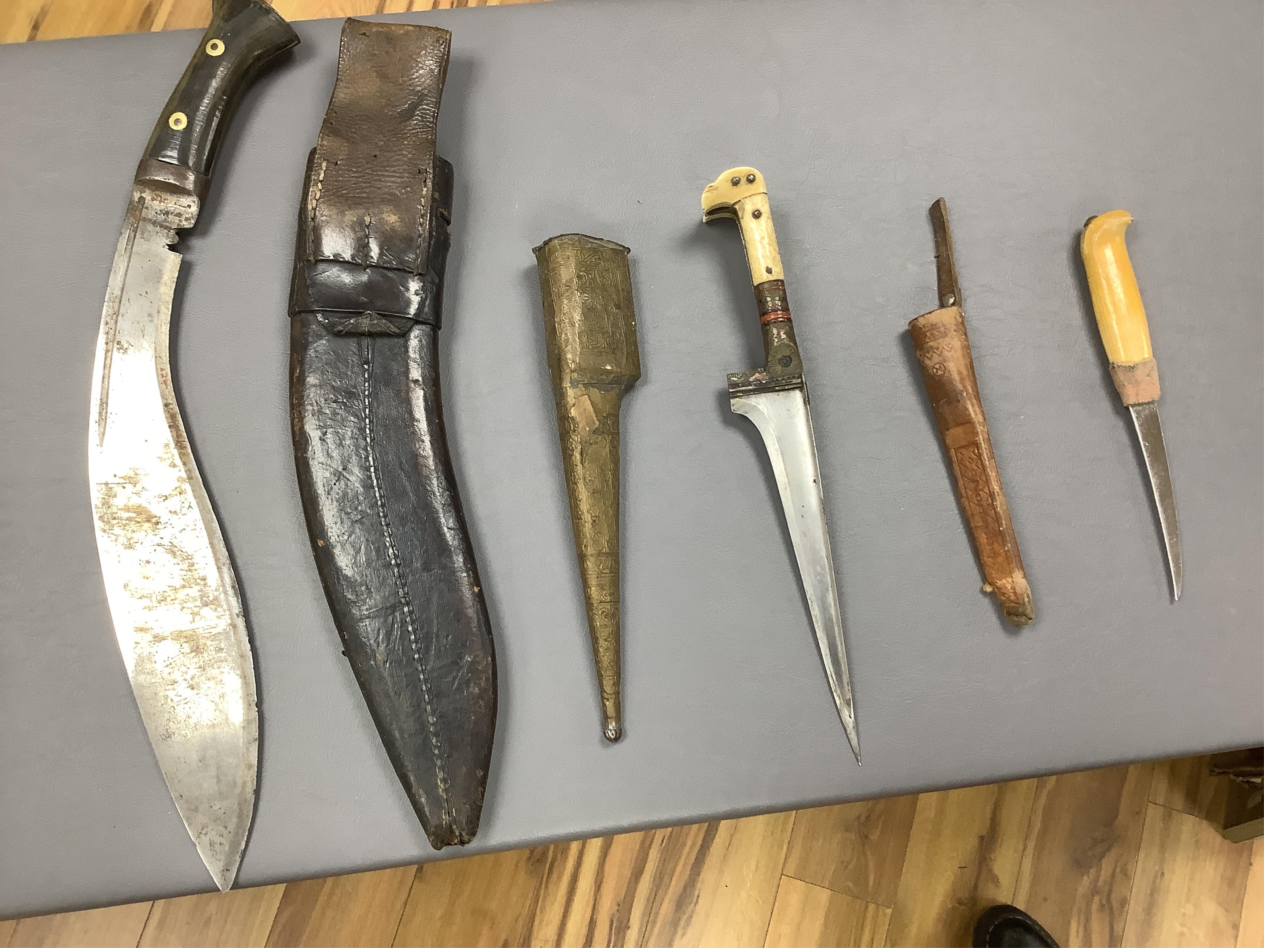Eighteen assorted world weapons comprising a silver jambya (pommel missing), a knobkerry, a dha, two kris (one with handle missing), a lohar, three kukris, a djambok, a Chinese trousse, a chora, a flyssa, five others and